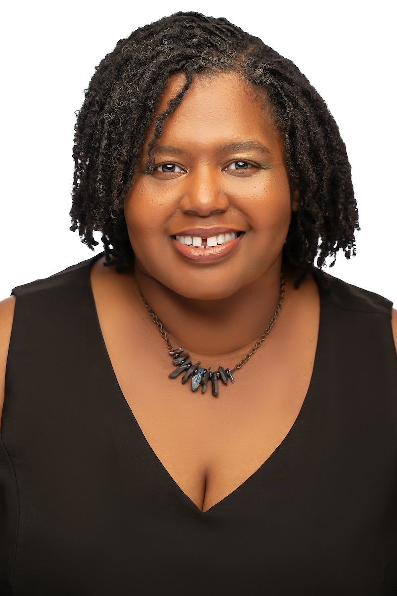 Black woman in black dress and charm necklace
